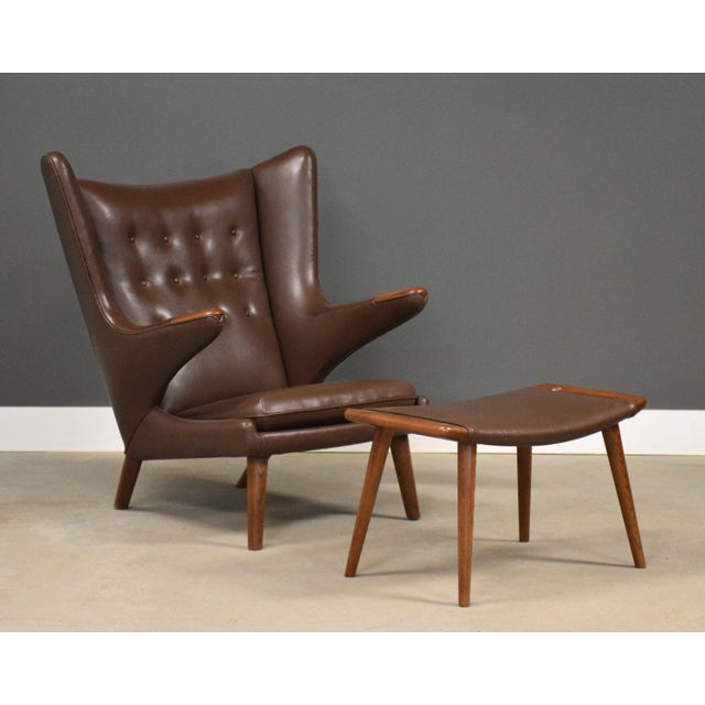 An original signed teak Papa Bear chair designed by Hans J. Wegner for AP Stolen in brown vinyl. Minor imperfections in...