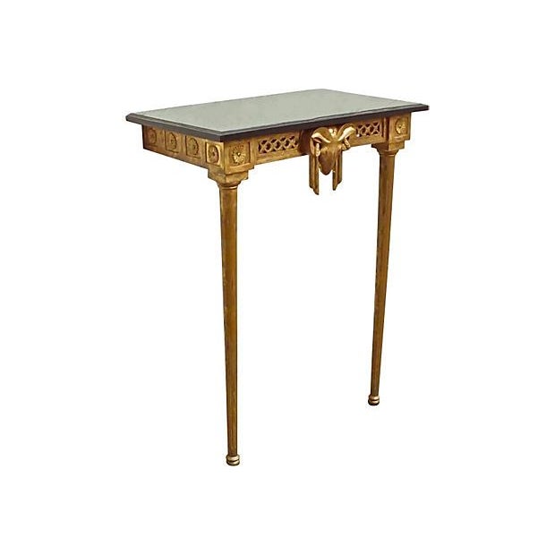This vintage, French console table features a wall mounted, gilt hand carved frame and legs with a black granite top....