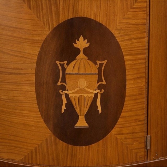 This is a striking pair of neoclassical style hand hewn satinwood and mahogany inlaid demilune cabinets. They are...