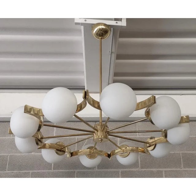 Superb chandelier for its characteristic concave circular structure, unique design for the brass housing of the spheres....
