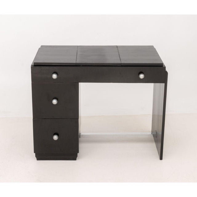 Art Deco Ebonized Writing Desk, with central leather writing surface atop a long drawer above two drawers with silver-tone...