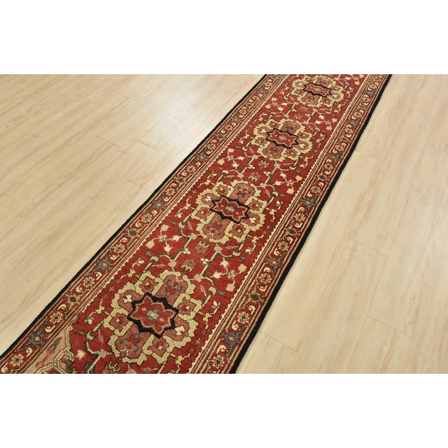 A traditional Heriz runner hand-knotted with an all-wool pile on a cotton foundation. This oriental rug features a row of...
