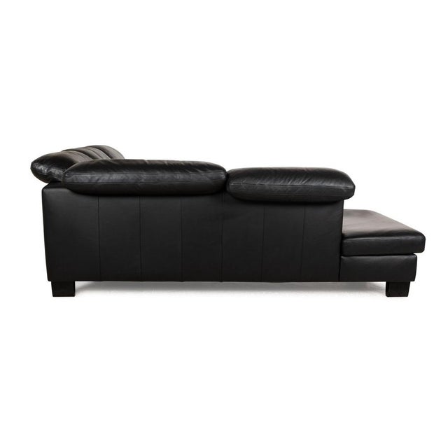 The corner sofa by Willi Schillig is covered in black leather and stands on angular black wooden feet. It is characterized...