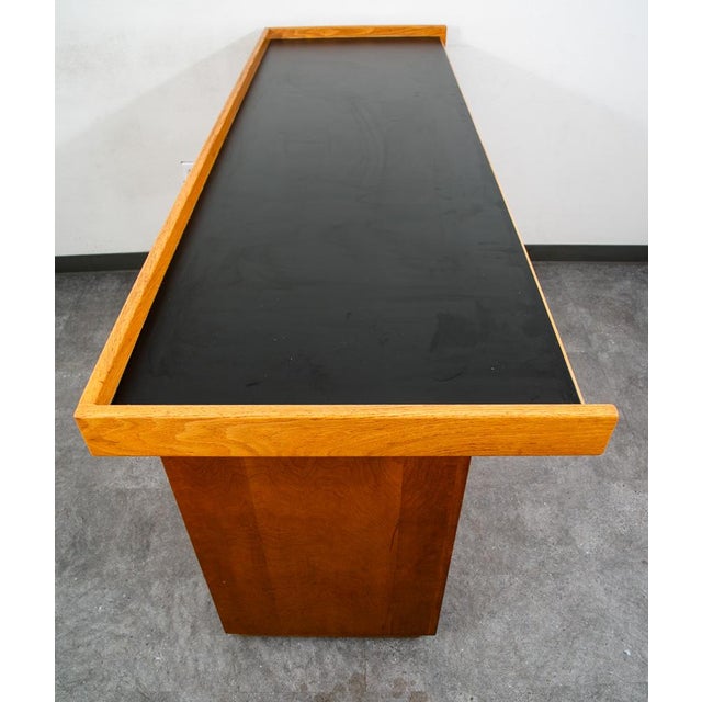 Custom black formica and white oak bar with shelving and cabinet below. Unknown maker. The 3 doors below the main surface...