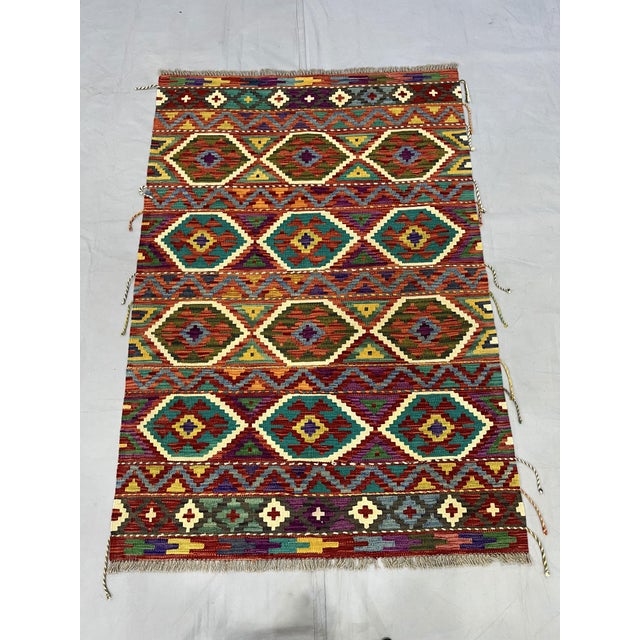 This Afghan Chobi wool kilim features a colorful Khorjin saddlebag-inspired design with repeating geometric diamond motifs...