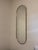 Edged with a slim brass band, this minimalist wall mirror curves an elongated oval for a modern and elegant silhouette....