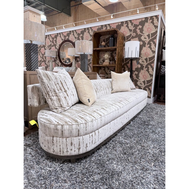 An exceptional Tomlinson Cambria sofa by Theodore Alexander showcasing a fluid curved silhouette with a refined...