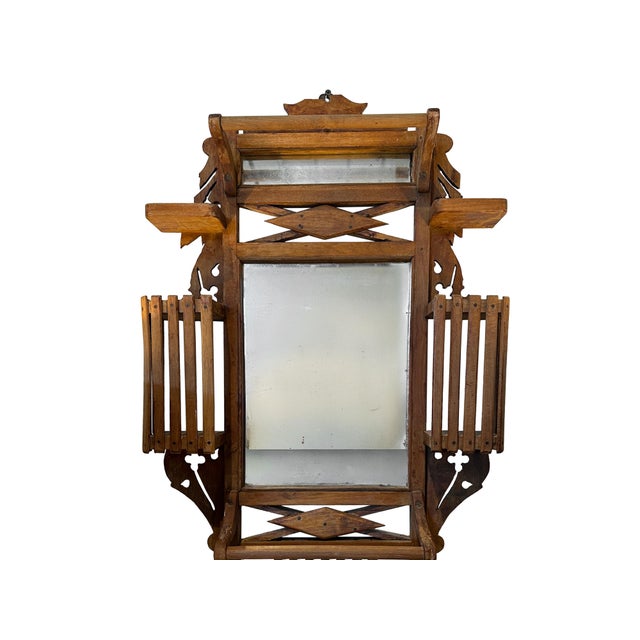 A highly architectural Eastlake wall mirror executed in warm-toned walnut, featuring incised geometric carving and layered...