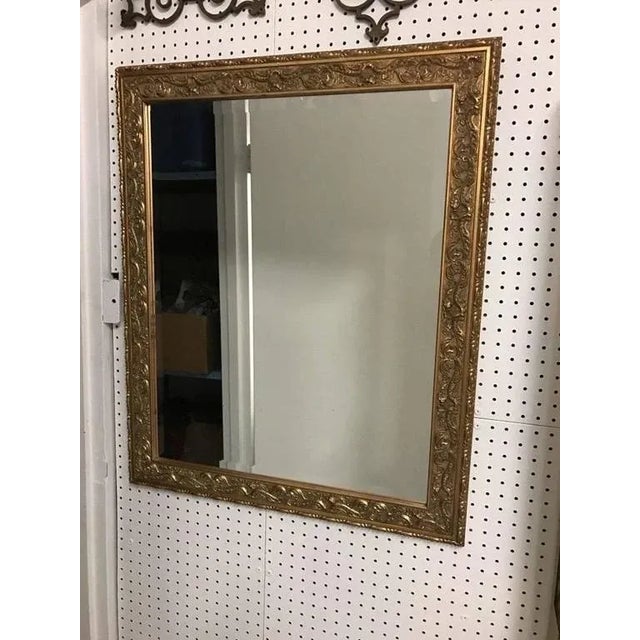 Stunning gilt wood mirror with beveled glass and hand-carved scroll work.