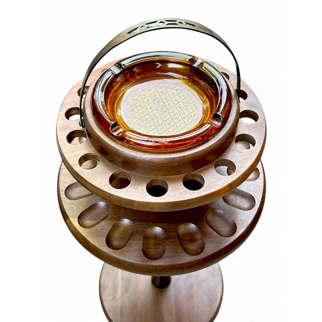 Freestanding walnut 16 hole pipe holder from Decatur Industries with matching amber glass ashtray. Measures 23” tall...