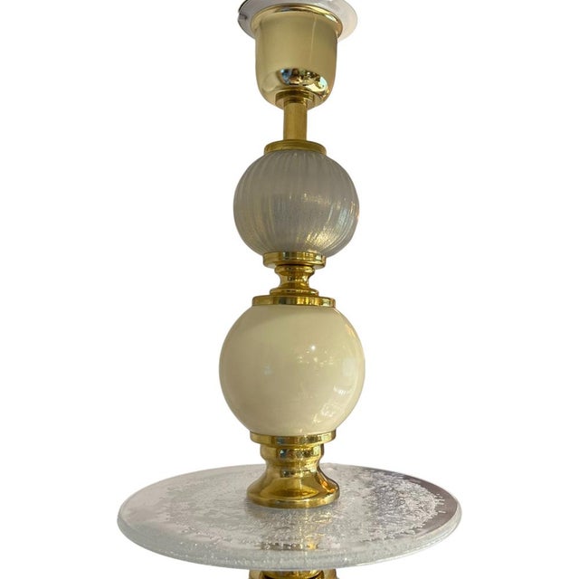 Table lamp with a central structure composed of blown glass and brass elements, with translucent white and blue details...