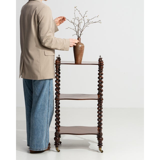 A 19th century English étagère in the Victorian style, constructed in wood with a three-tier shelving arrangement. The...