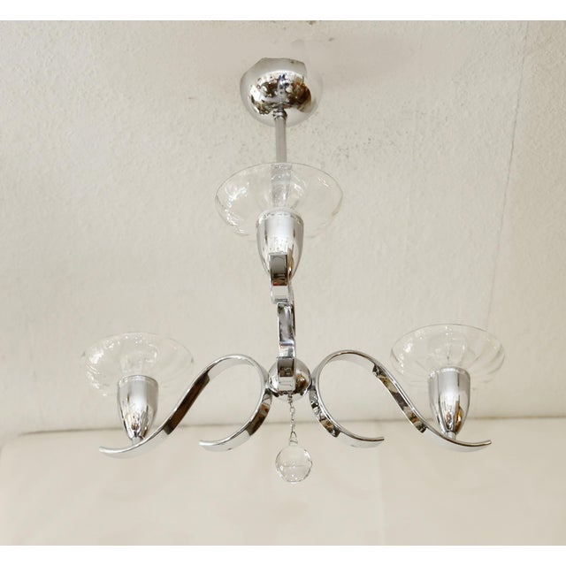 Nickel-plated Art Deco chandelier, made in the 1920s/30s. Three curved arms with crystal glass shades. Closed at the...