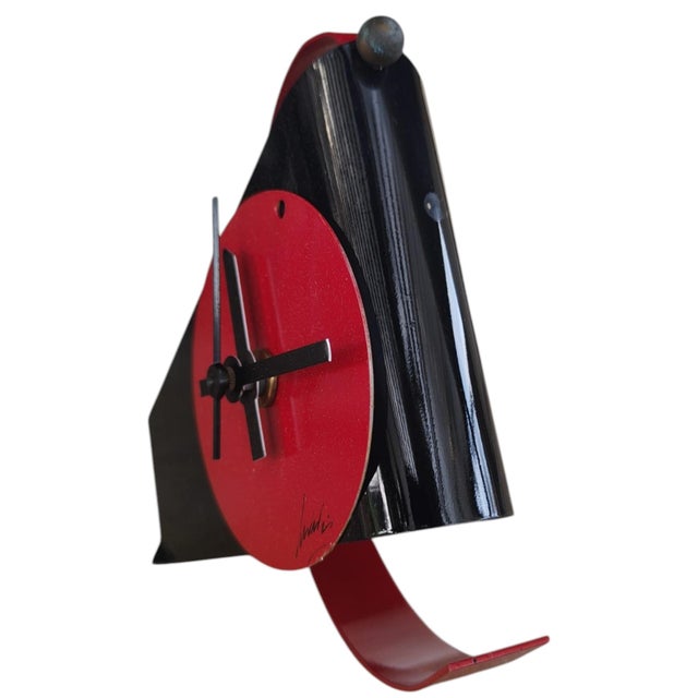 Table clock produced in the early 1980s, postmodern, made of lacquered metal, with a red circular dial on a black...