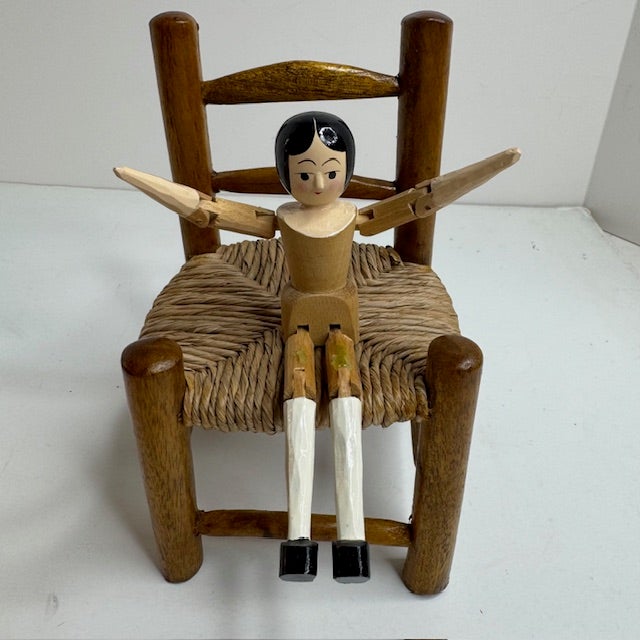 Charming mid-century wooden peg doll seated in a miniature rush-seat chair, produced by Eric Horne Co. and marked Made in...