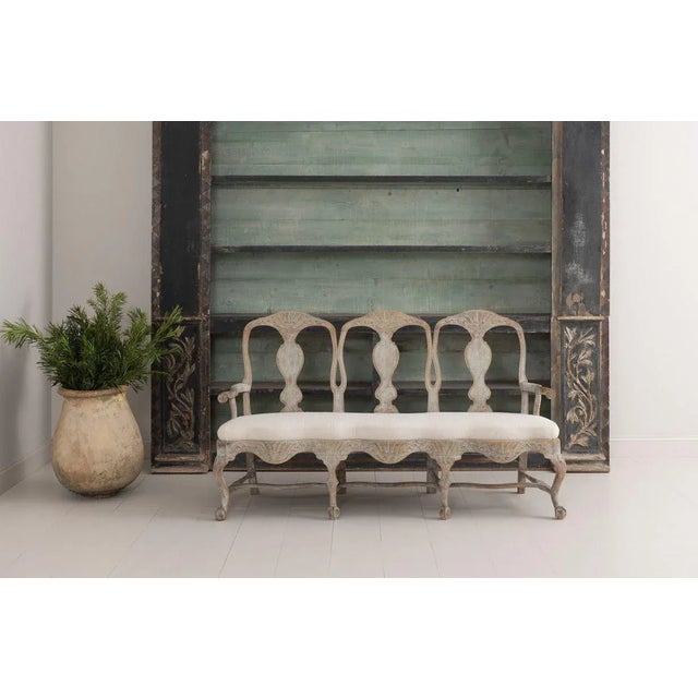 A richly carved, 18th century Swedish sofa bench from the Rococo period, newly upholstered linen. This beautiful settee...