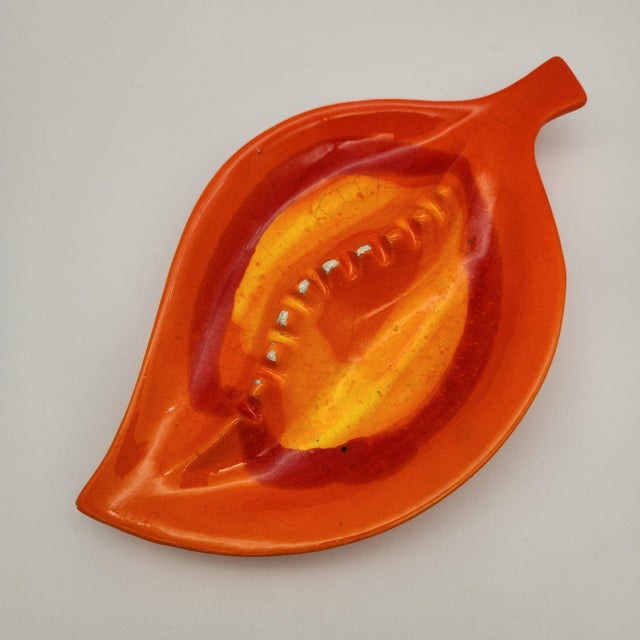 Mid-century ceramic leaf-shaped ashtray in vibrant orange and yellow drip glaze with sculpted central vein detail