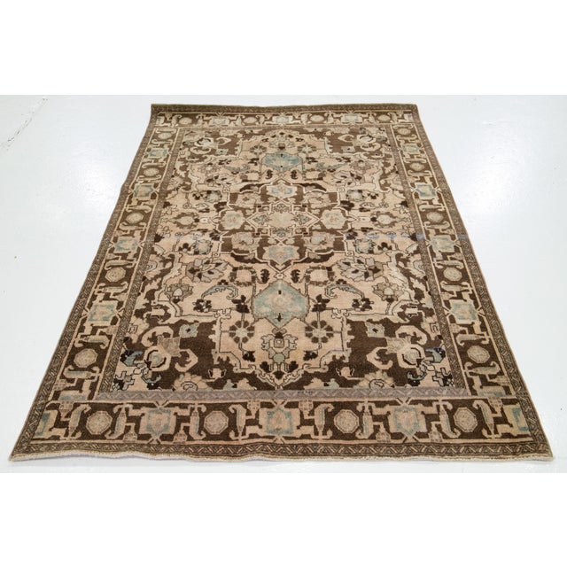 This vintage handmade wool rug has a brown and tan field with brown and blue accents all over the design. This rug...