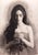 This charcoal drawing depicts a young woman gently cradling a white flower, her expression serene and introspective. The...