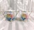 This is a white and teal blue sugar and creamer set by Reinhold Schlegelmilch RS Prussia. The set has pink and yellow...
