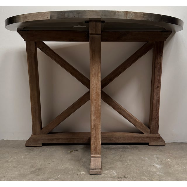 Demi-lune console in driftwood finish with metal top. Metal has slight distressing with nail head/ tack trim