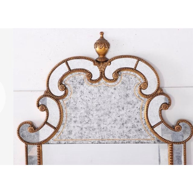 A striking Lillian August for Hickory White neoclassical wall mirror, featuring an elegant antiqued-gold finish, bead...