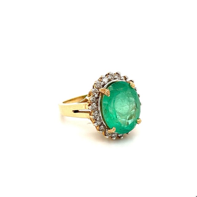 Centering a 6.88 Carat Oval-Cut Colombian Emerald, framed by 1.65 Carats of Round-Brilliant Diamonds, and set in 14K...