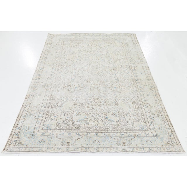 Transform your space with this authentic Antique Persian Kerman wool rug, featuring a delicate floral medallion surrounded...