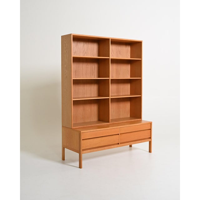 Oak bookcase composed of two stacked elements, with open shelves and a base with four drawers. Scandinavian production,...