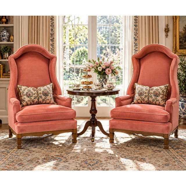 A striking pair of vintage Hollywood Regency hooded wingback chairs upholstered in soft salmon-pink velvet. Inspired by...