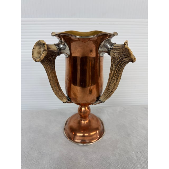 Design Plus Gallery the Sterling Silver + Copper Vase. The vase has three handles made of antlers that have the implied...
