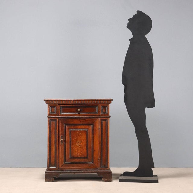 Baroque walnut bedside table. Drawer in the lower section, paneled door with a later central inlay, maple trim, and...