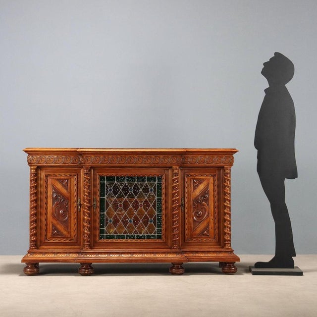 Neo-Baroque walnut sideboard. Split front with a projecting central element, including a leaded stained-glass door and...