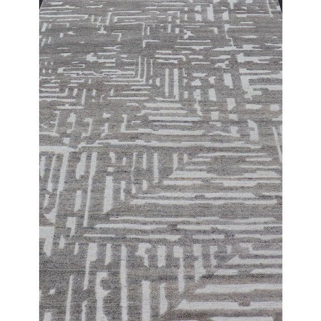Measures 5'8 x 8'5 This modern area rug was hand-knotted in during the 2020's. The field features a sub-geometric abstract...