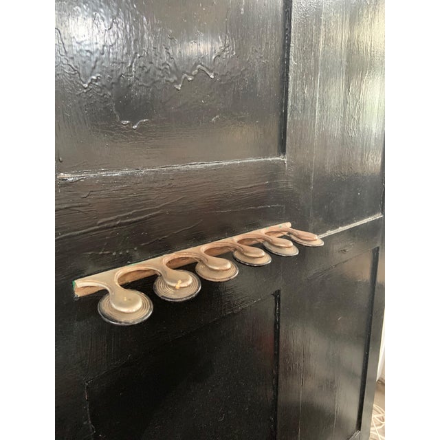 This black hand painted vintage European hallway rack includes 6 brass hooks under a ladder shelf along the top. There is...