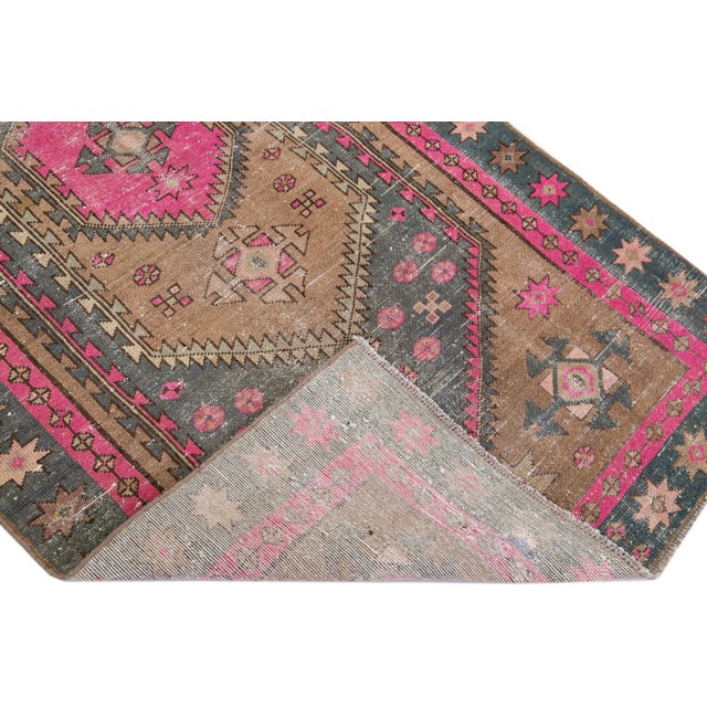 Beautiful vintage Persian distressed hand-knotted wool rug with a pink color field. This piece has a gray frame and...