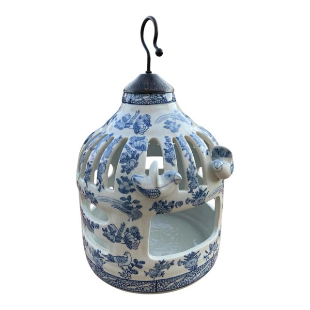 A substantial blue and white Chinoiserie-style ceramic birdcage sculpture featuring two perched birds, open fretwork...