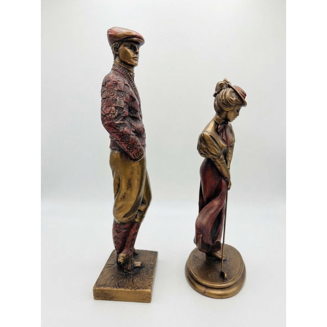 A charming pair of vintage 1989 Austin Productions golfer sculptures featuring a distinguished gentleman and elegantly...