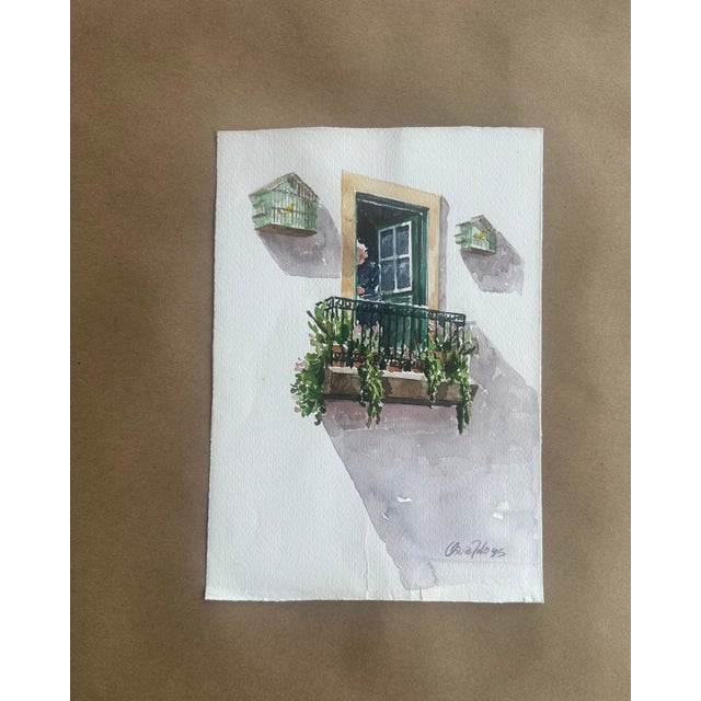A charming original watercolor depicting a sunlit European-style balcony with lush greenery and two small birdcages...