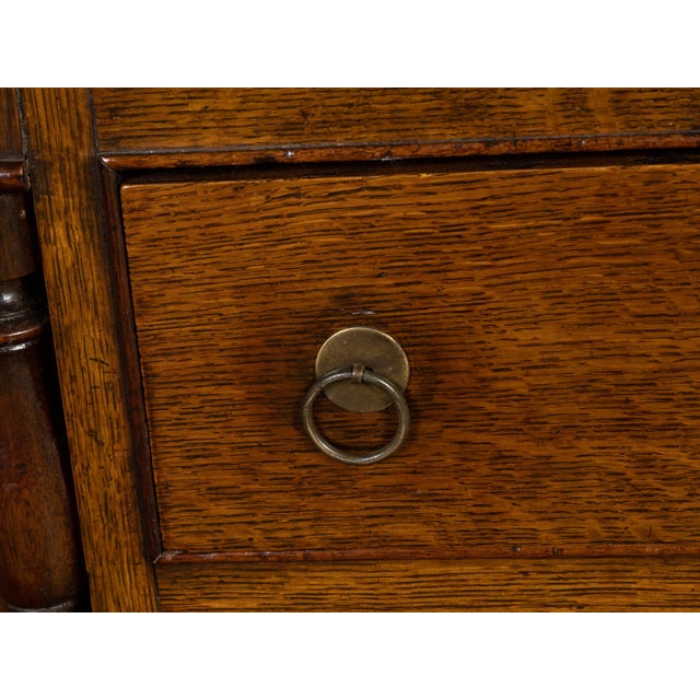 An English georgian period oak dresser from the 18th century with open shelves, six drawers, two doors and bone-inlaid...
