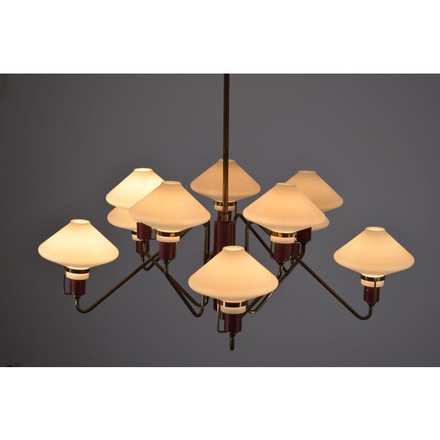 An elegant 1950s Italian chandelier by Lumen, featuring a refined 10-light design. The brass structure features sinuous,...