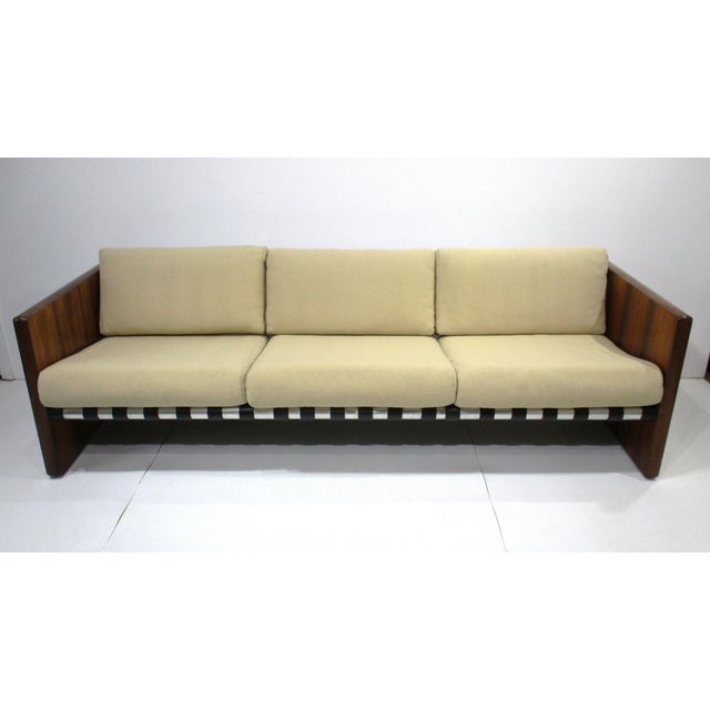 A very well-crafted luxurious case tuxedo styled sofa with Brazilian rosewood slab sided legs, satin black leather straps...