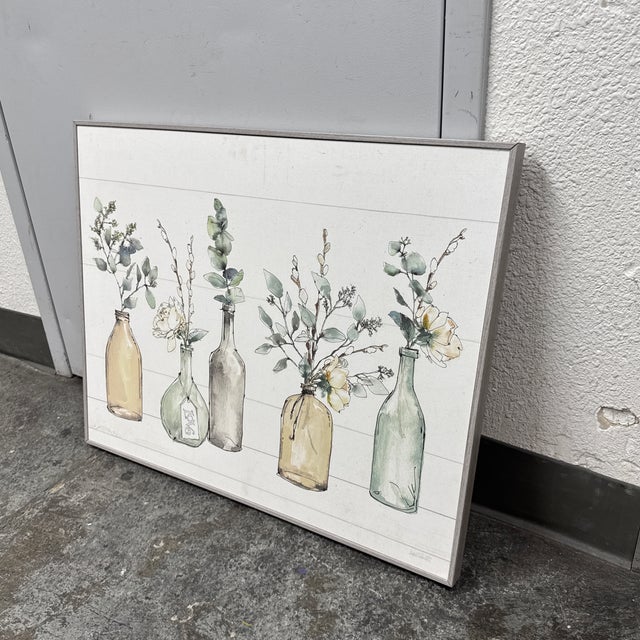 Design Plus Gallery presents a Botanical Floral Bottles Wall Art from Stupell Home Décor. The artwork depicts an...