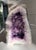 A striking natural amethyst cathedral geode featuring richly saturated purple crystal formations that transition...