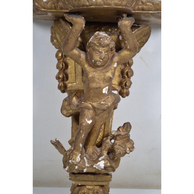 XVIIIth century. Small wall console in stuccoed and gilded wood, the scalloped top supported by Zéphir. Lacks Height 14,17...