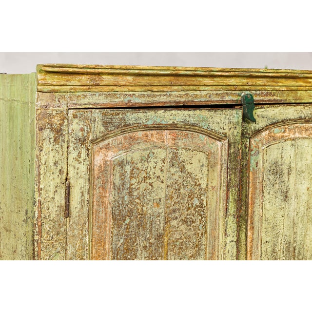 A small distressed green painted Indian cabinet from the 19th century with paneled doors and two lower drawers. This 19th-...