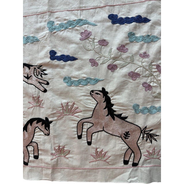 Hand-embroidered Suzani panel from Uzbekistan, worked in fine floss on a cream cotton ground. Ten blush horses move across...