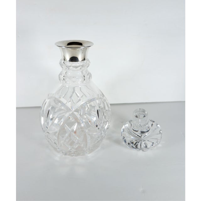 A cut crystal decanter with sterling silver top rim made by John Grinsell & Sons, Birmingham, England. Sold by R&W Sorley...