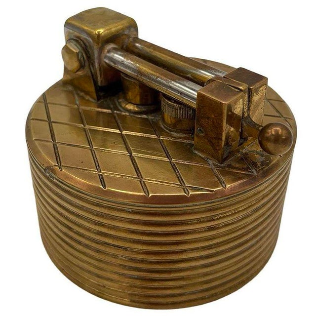 This 1950s Brilux for Dunhill Swiss brass lift-arm table lighter combines timeless elegance with exceptional...