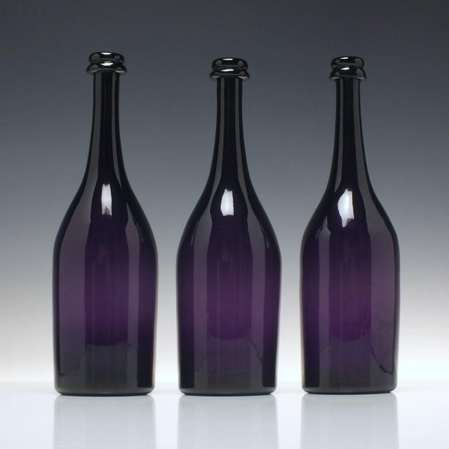 A fantastic set of three amethyst glass serving bottles dating to around 1830. Very unusual string rims and large polished...